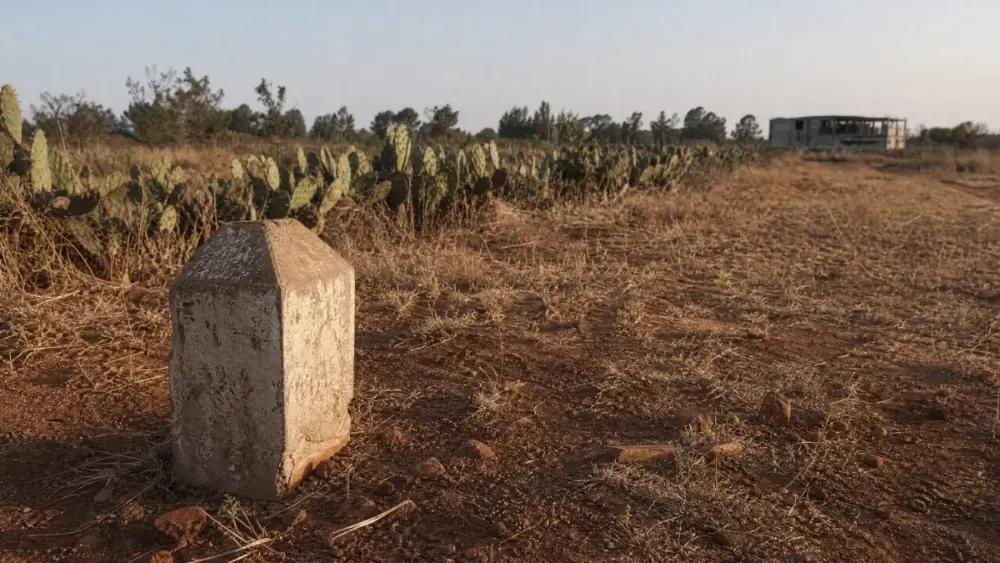 A weathered concrete survey beacon marking a plot boundary in red earth outside Nairobi